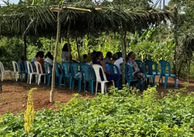 Habitants d'Ovangul réunis sous un abri de branchages sur le terrain de la future boutique solidaire