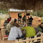 Habitants d'Ovangul rassemblés sous l'abri pendant les travaux de toiture